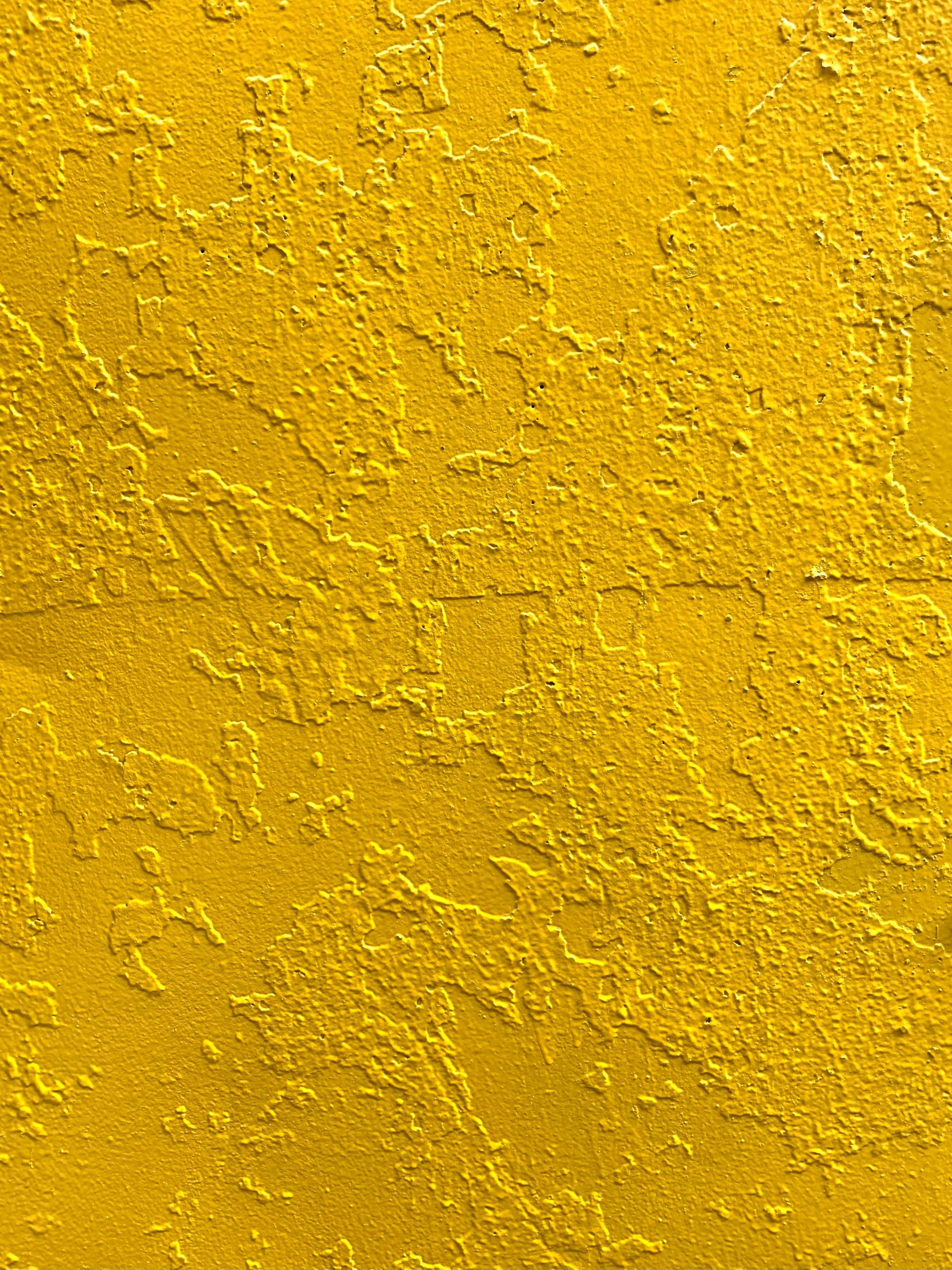 Bright yellow stucco wall with rich texture for creative backgrounds or design elements.